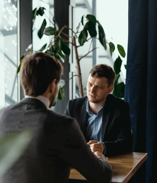 Focused businessman listening to business partner talking during discussion, thinking over his ideas while sitting at the table